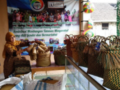 Mariatul Asiah among the purun handicrafts that she markets through Komunitas Pelangi. © Budi Kurniawan